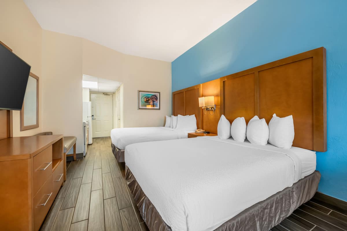 Ein Hotelzimmer mit zwei Betten, einem Holzschrank, einem Fernseher und einem Bild an der Wand.