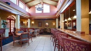 A spacious dining area with high ceilings, large windows, and a central bar.