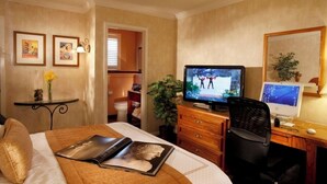 Hotelkamer met een bed, een bureau met een computer, een televisie en een kleine tafel met een bloevas.