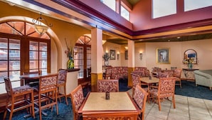 A hotel lobby with a bar, seating areas, and a view of the outside.