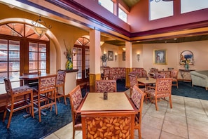 A restaurant with booths and tables, large windows, and a high ceiling.