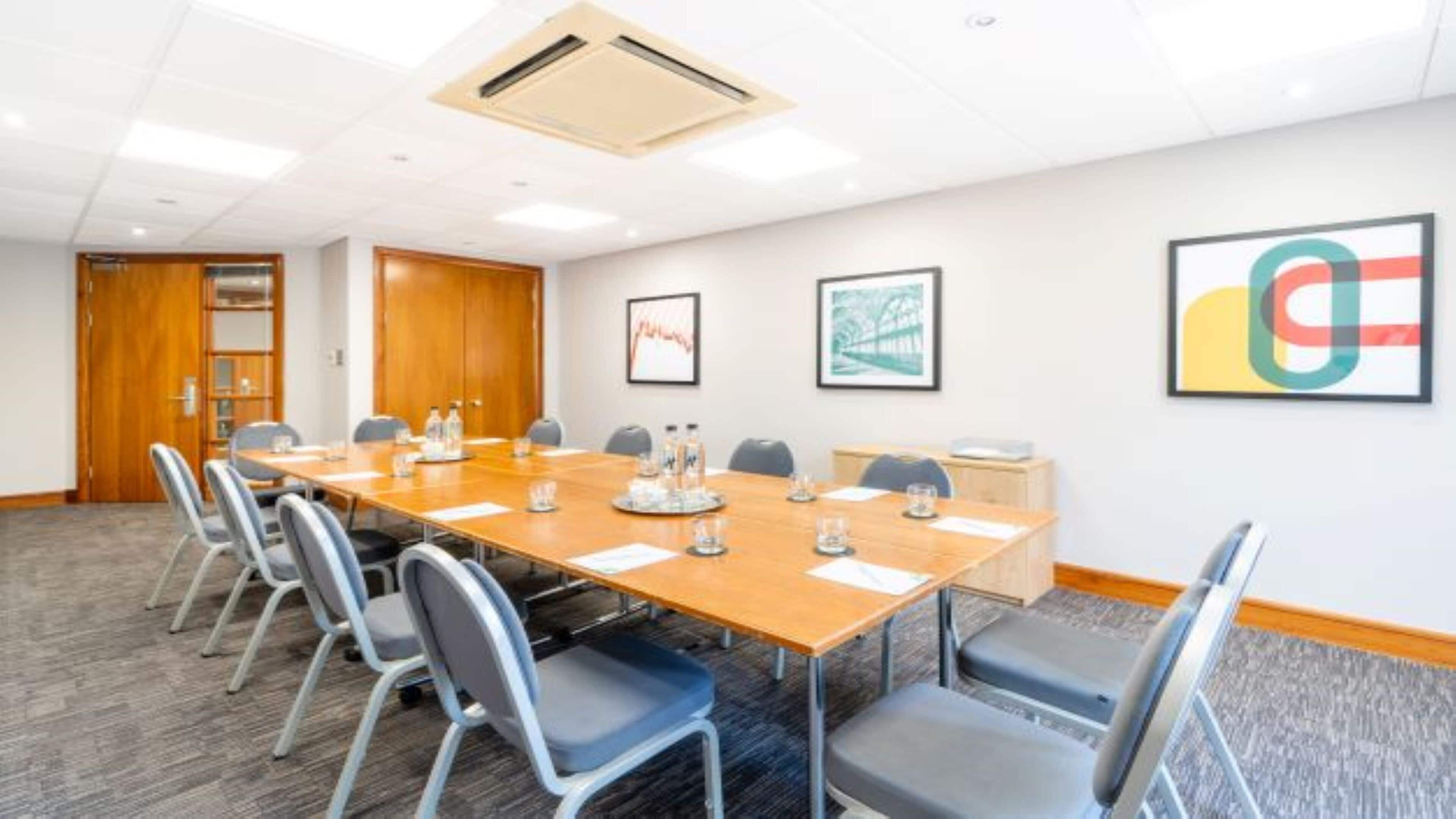 A conference room with a long table, chairs, and a wooden door.