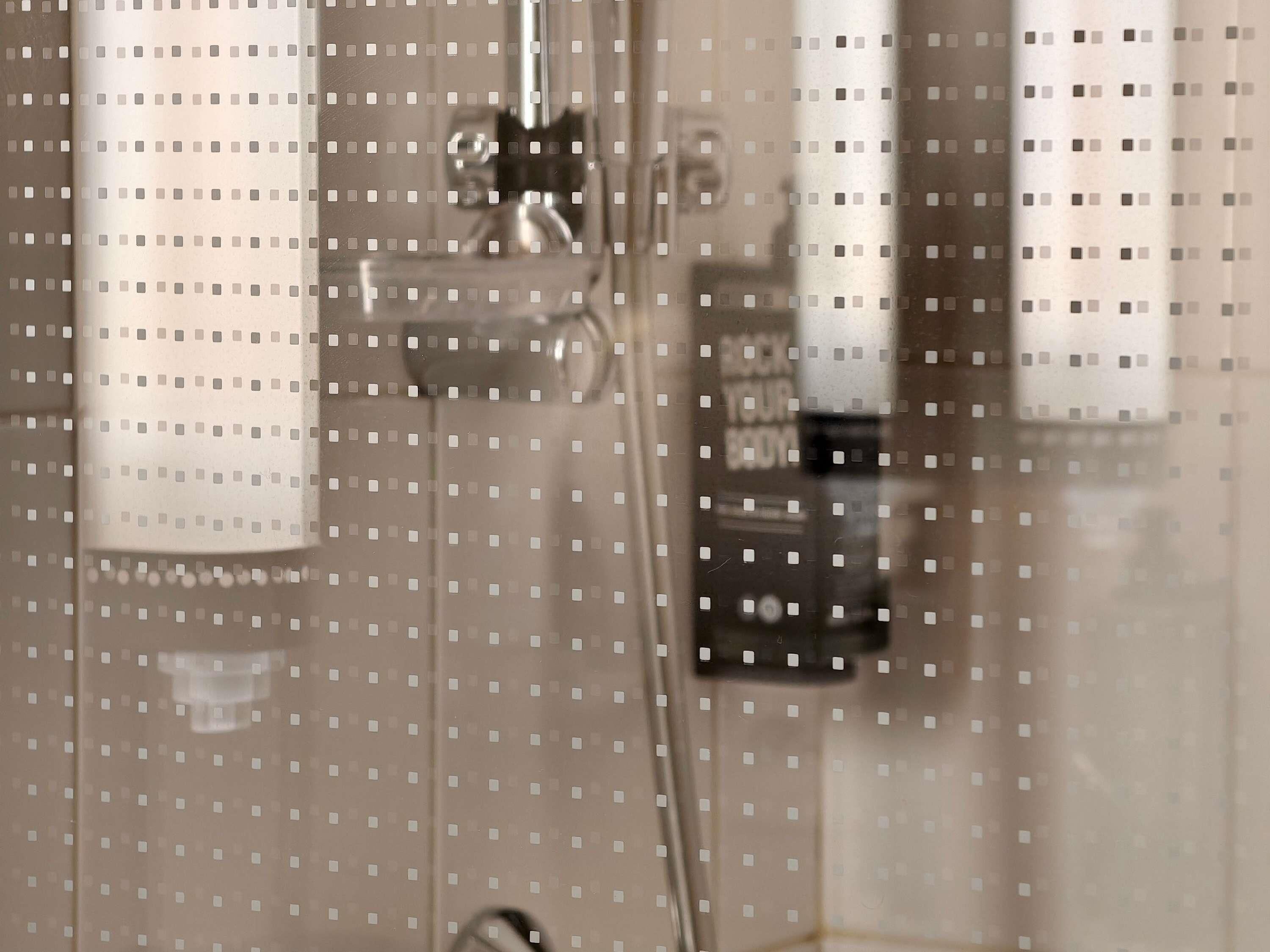 A bathroom with a glass partition, a shower area, and a visible towel rack.