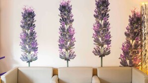 Un salon moderne avec un canapé beige, des tables basses en verre et des décorations florales fixées au mur.