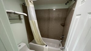 Un baño con inodoro, bañera, cortina de ducha y toallero.