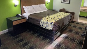 Una habitación de hotel con cama, mesitas de noche, teléfono y lámpara de pared.