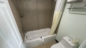 Un baño con bañera, inodoro y cortina de ducha.