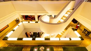 A modern hotel lobby with a central staircase, a reception desk, and a seating area. - Millennium Hotel London Knightsbridge (London)