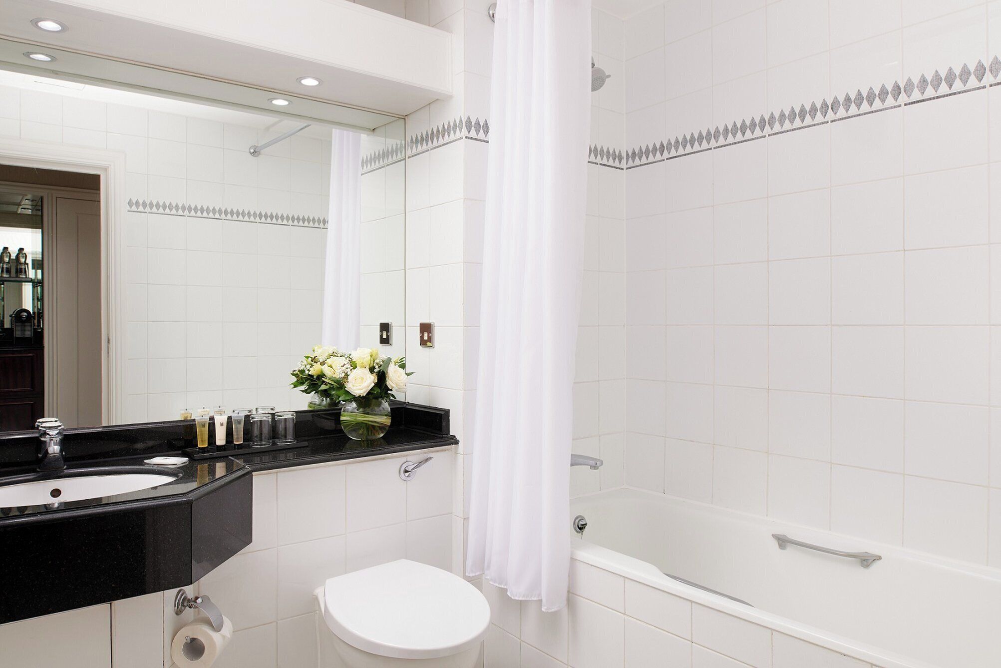 A modern bathroom with a black countertop sink, white toilet, and a bathtub.