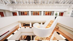 A modern hotel interior with a central spiral staircase, multiple floors, and large windows. - Millennium Hotel London Knightsbridge (London)