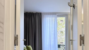 A bedroom with a bed, curtains, and a view of the outside. - Best Western Hotel Le Montparnasse (Paris)