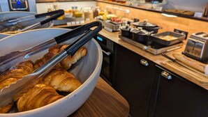 A buffet area with a bowl of croissants and various breakfast items. - Best Western Hotel Le Montparnasse (Paris)