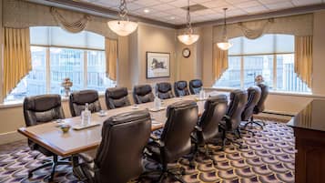 Une salle de conférence avec une longue table, des fauteuils en cuir et de grandes fenêtres.
