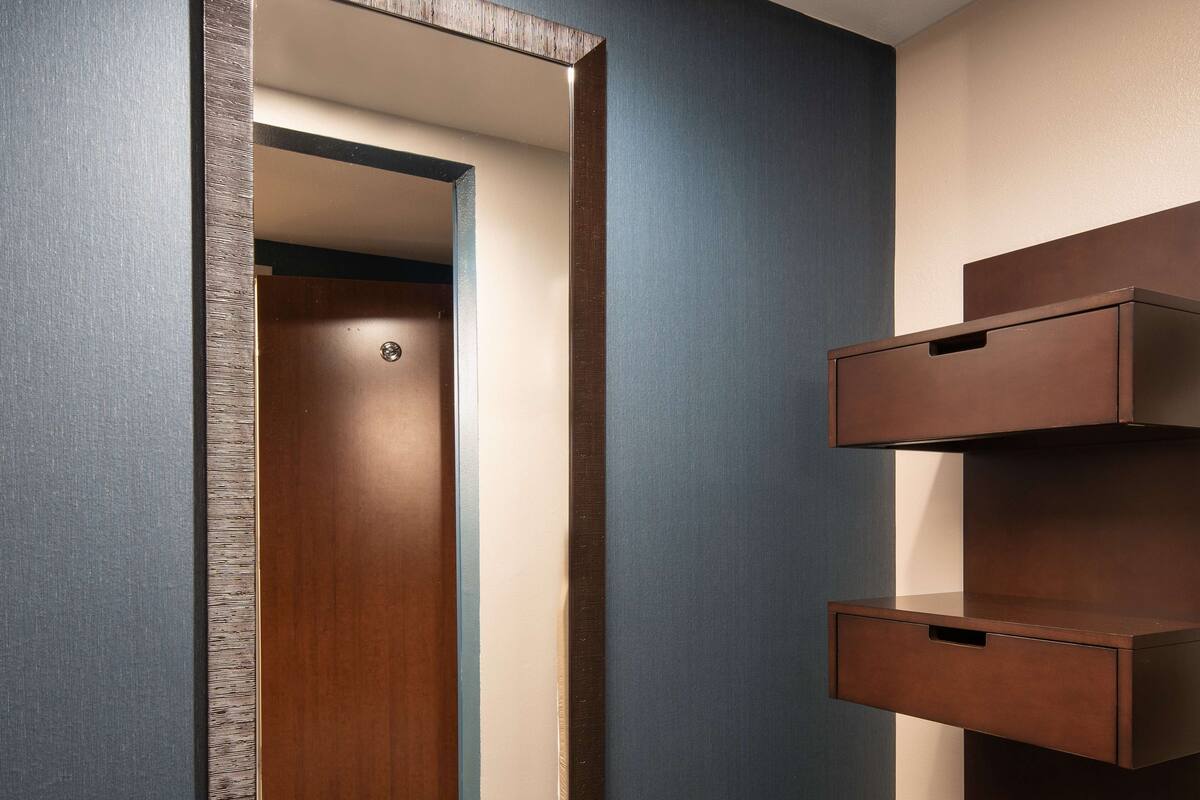 A hallway with a wooden door, a blue wall, and a built-in wooden shelf unit.