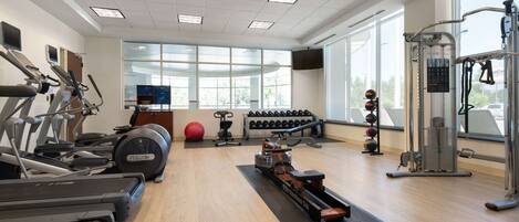 A gym with treadmills, dumbbells, a rowing machine, and a weight stack.