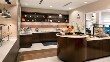 A modern kitchen with a central island, built-in shelves, and a variety of food items displayed.