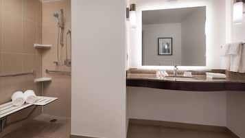 A modern bathroom with a shower, a sink, and a towel rack.