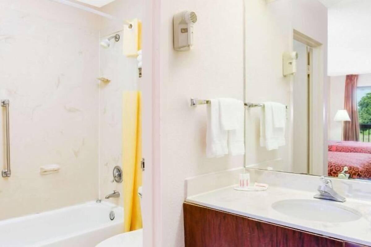 A bathroom with a bathtub, a sink, a mirror, and a towel rack.