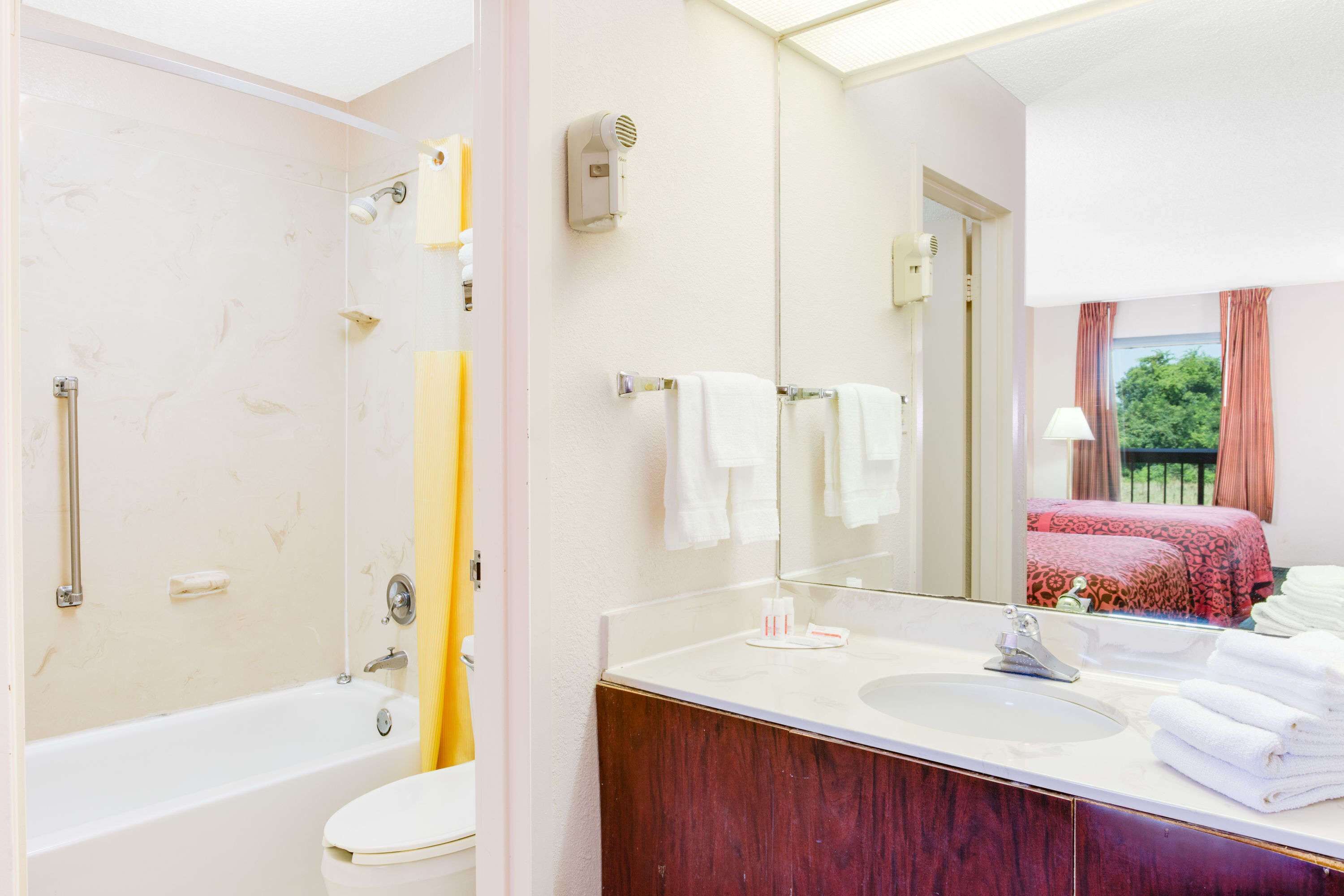 Un baño con bañera, lavamanos, espejo y ducha.