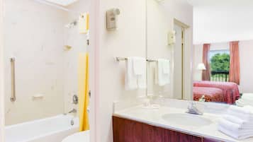 A bathroom with a bathtub, a sink, a mirror, and a shower.