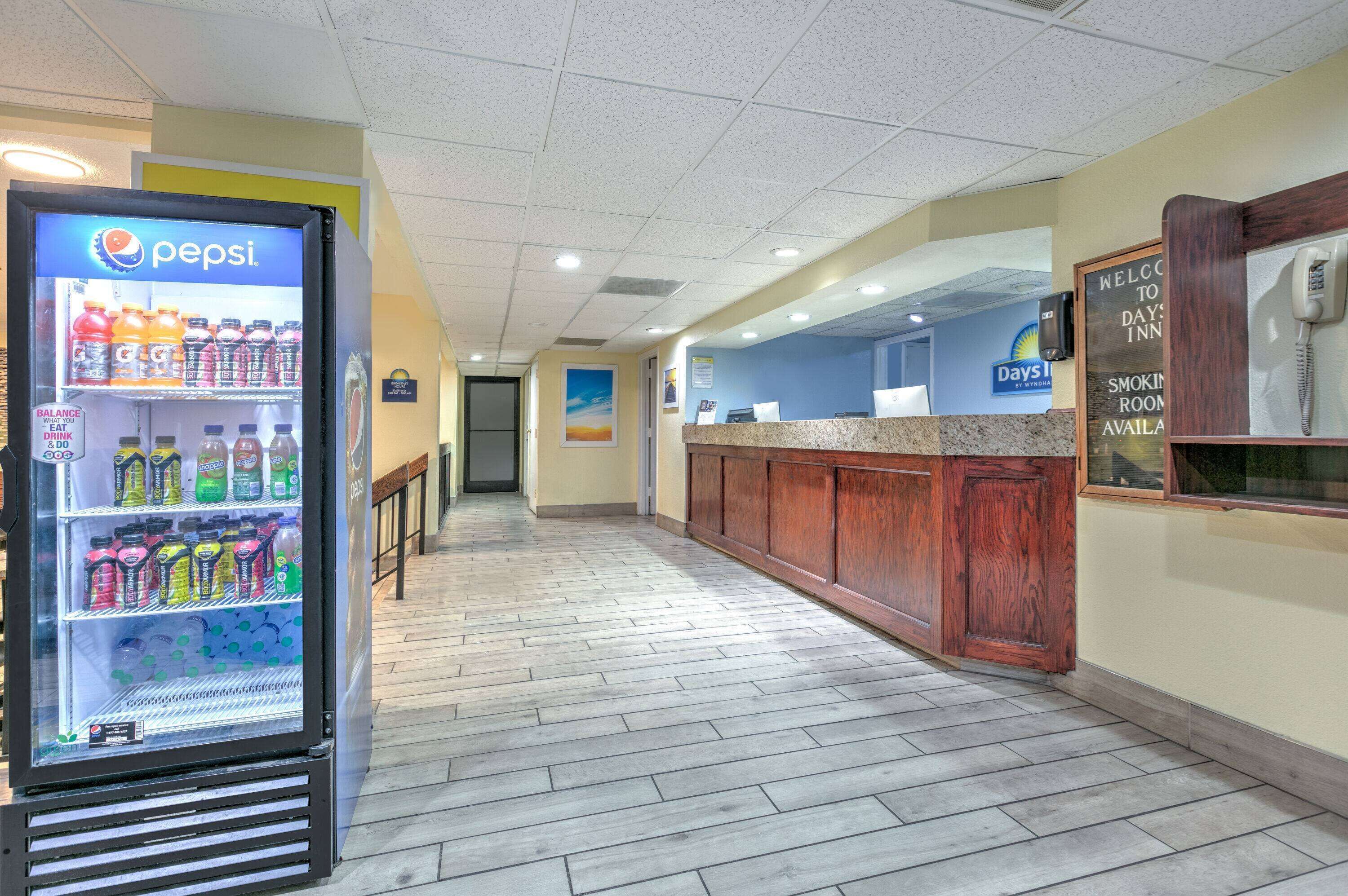Un pasillo con un refrigerador de Pepsi, una mesa de recepción y un letrero que indica una sala de fumadores.