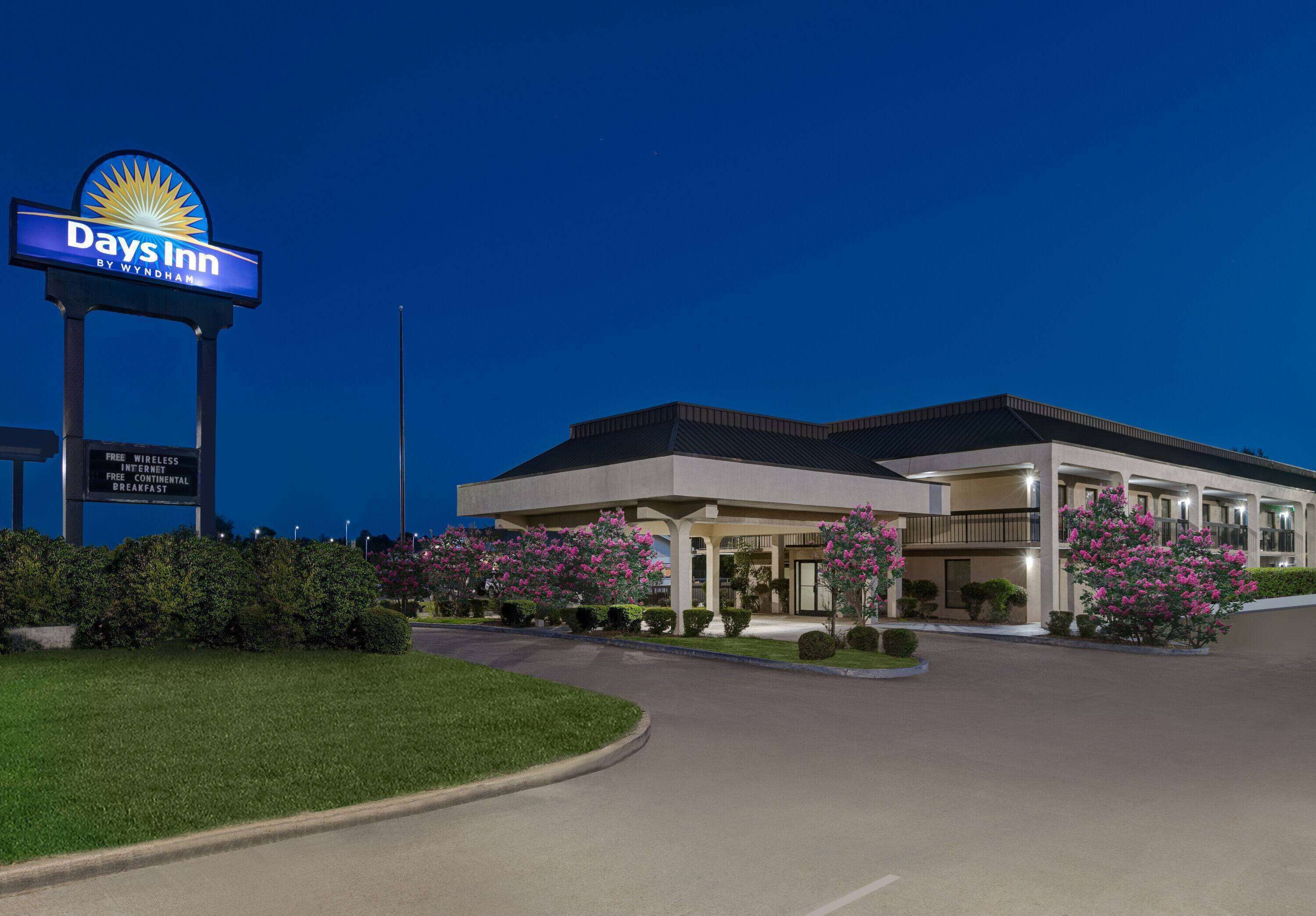 Un hotel Days Inn con un letrero llamativo, un estacionamiento y jardines bien cuidados.