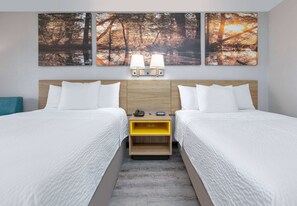 Habitación doble con dos camas, cabecera de madera, mesita de noche con lámpara y teléfono en la pared.