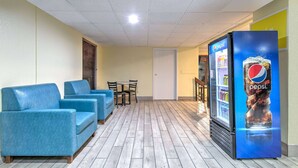A lobby with blue sofas, a Pepsi refrigerator, and a wooden floor.
