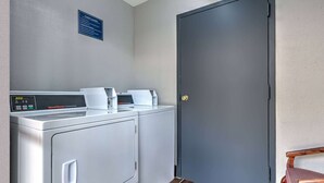 A laundry room with a Speed Queen commercial dryer, a washing machine, and a door with a sign above it.
