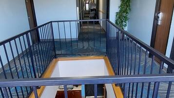 Eine Hotellobby mit einem offenen zentralen Bereich, einer Treppe und Blick auf den Flur.