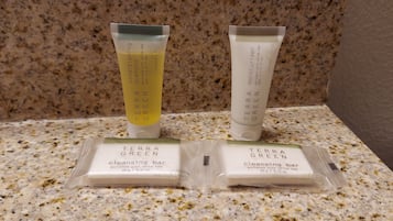 Zwei Flaschen Terra Green Shampoo und Conditioner sowie zwei Reinigungseifen auf einer fleckigen Arbeitsplatte.