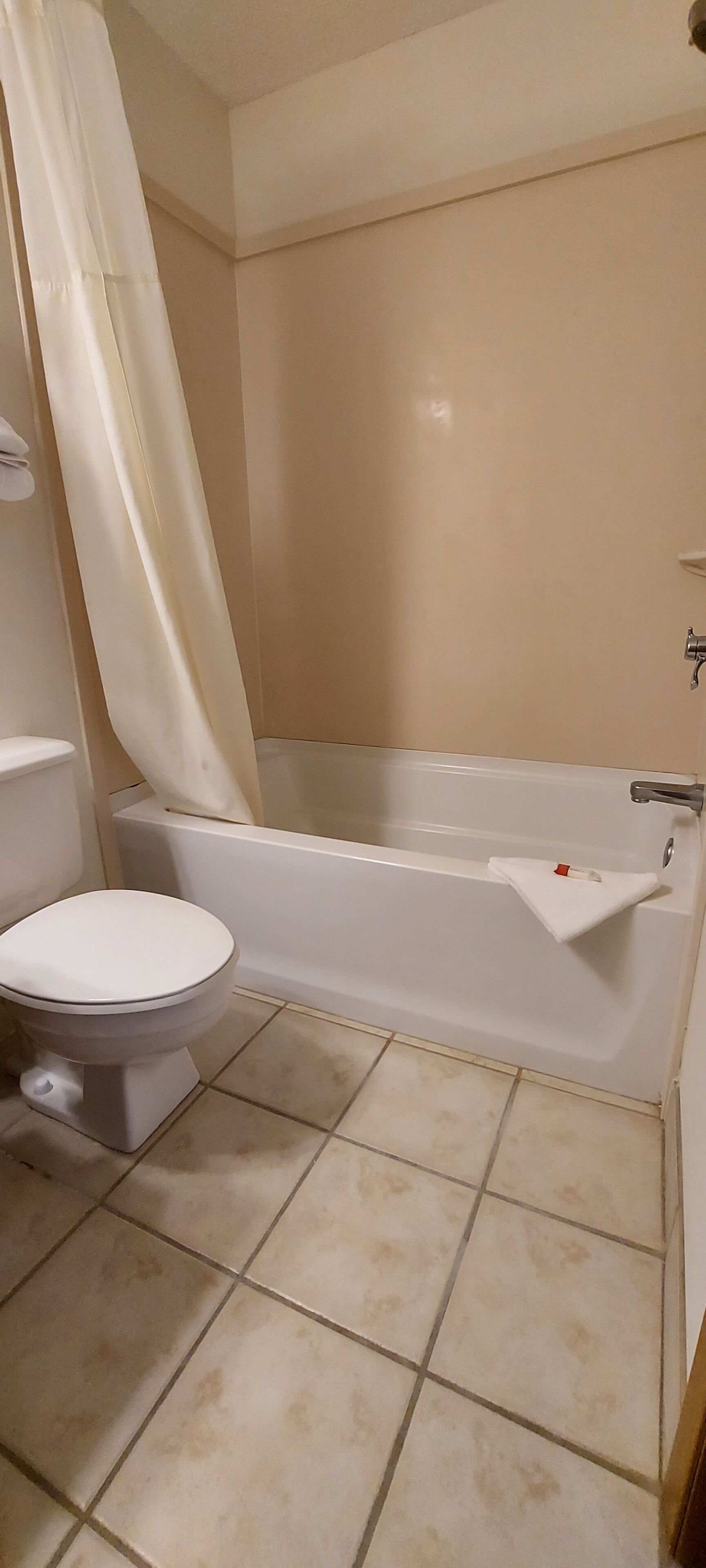 Un baño con inodoro, bañera y piso de baldosas.
