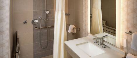 Ein modernes Badezimmer mit Dusche, Waschbecken und Spiegel.