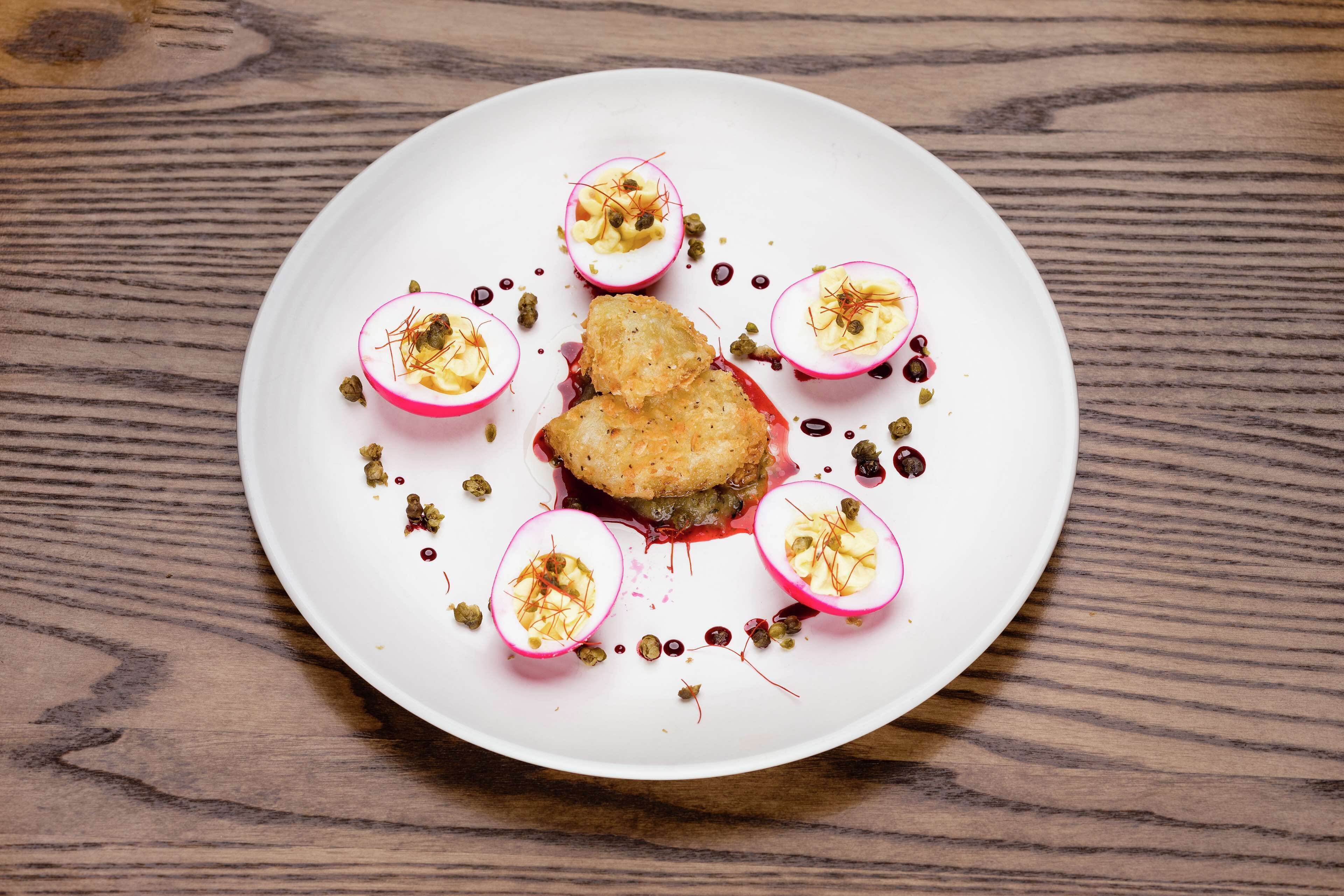 A white plate with a food dish, garnished with herbs and spices, on a wooden table.