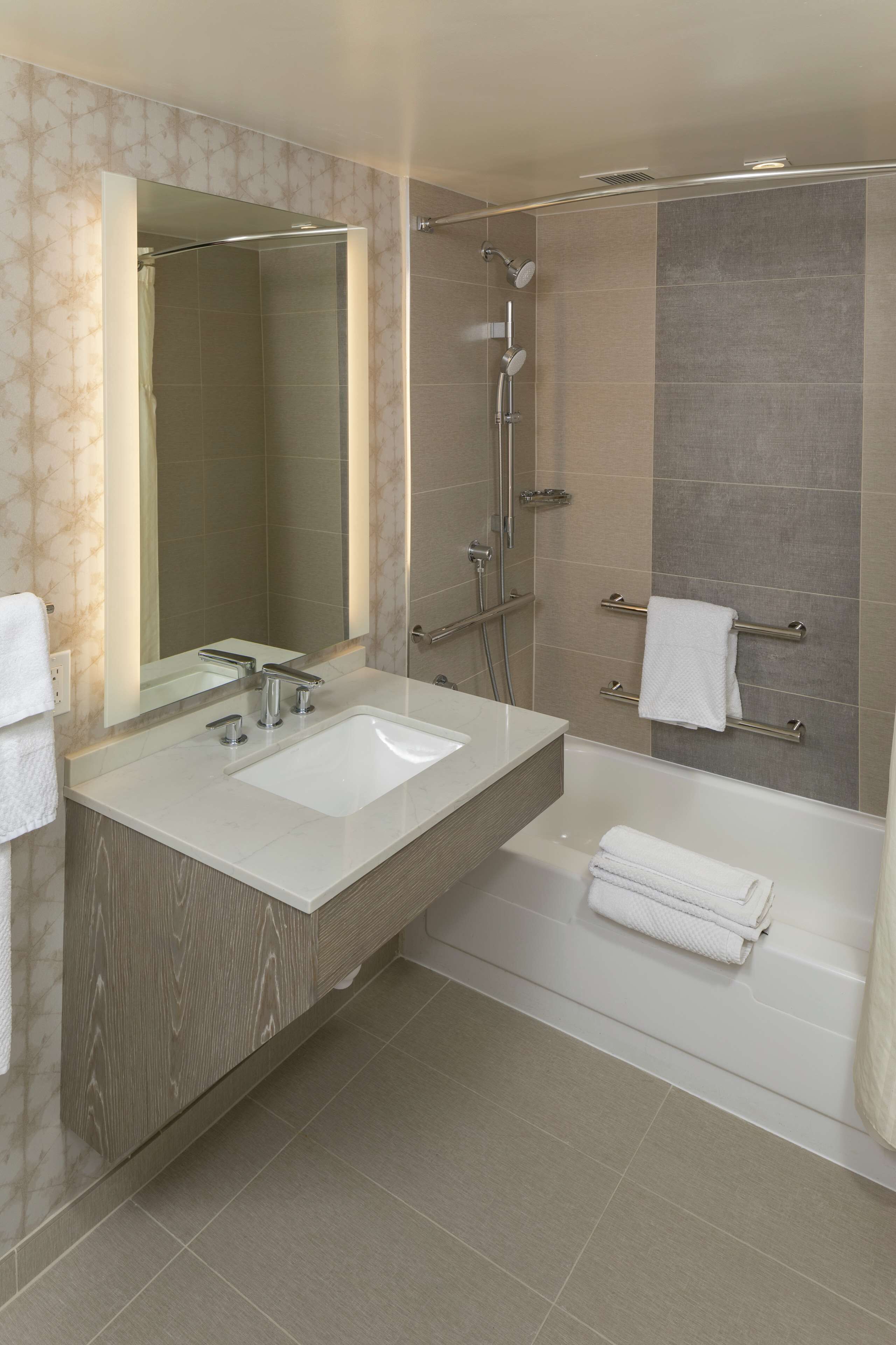 Un baño moderno con tocador doble lavamanos, un espejo grande, ducha con cabezal de ducha manual y bañera.