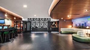 A modern lobby with a bar area, seating, and a cityscape mural.