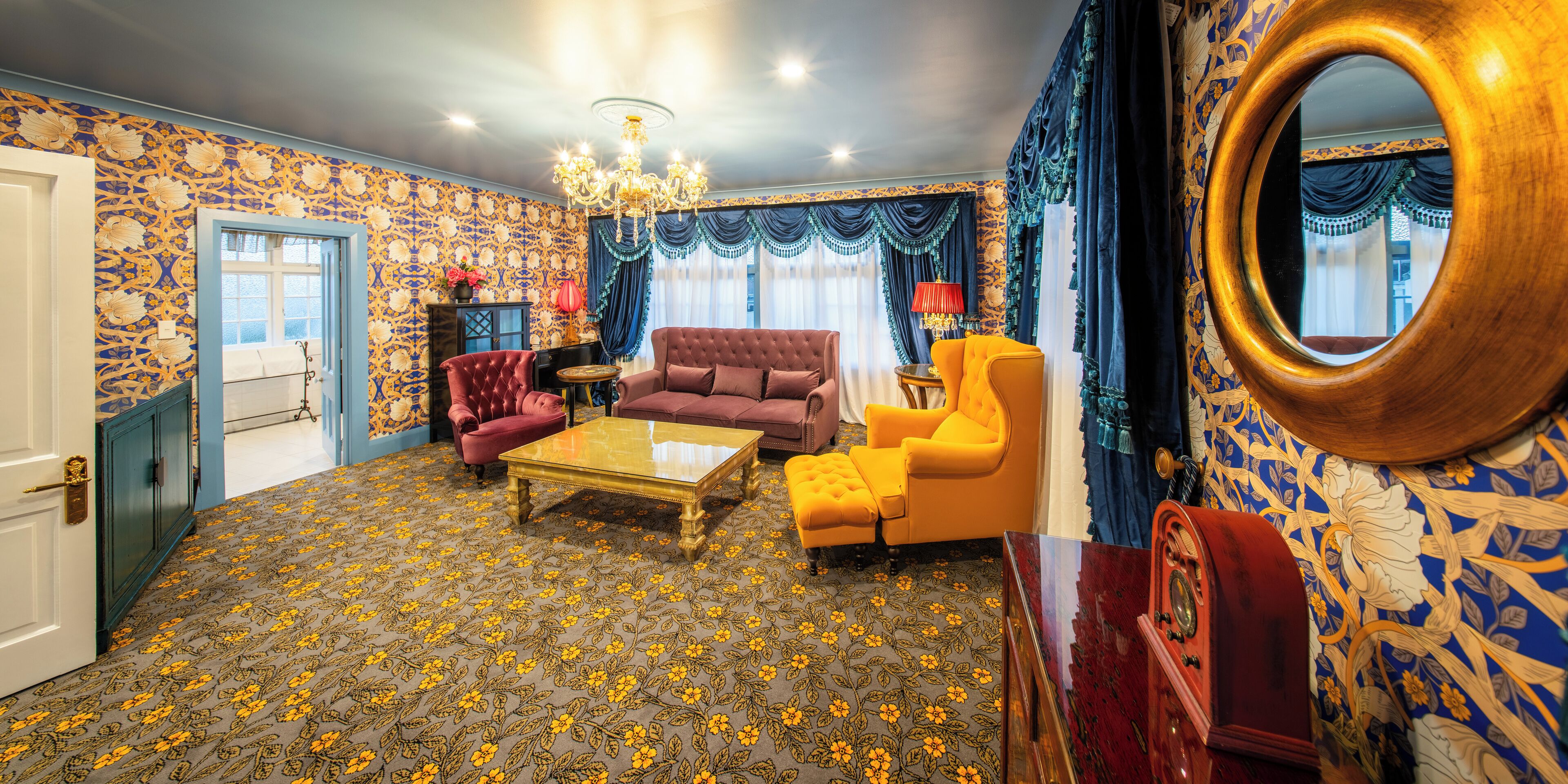 A room with a patterned carpet, a chandelier, and a large mirror.