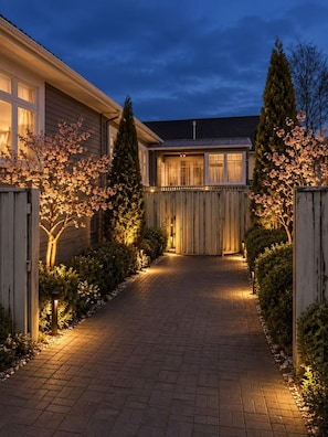 A residential driveway leading to a house with a wooden fence and flowering trees. - Prince's Gate Hotel (Rotorua)