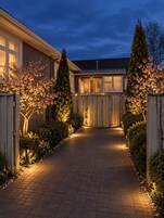 A residential driveway leading to a house with a wooden fence and flowering trees.
