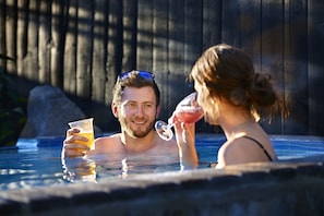Una pareja en un jacuzzi con una valla de madera al fondo.
