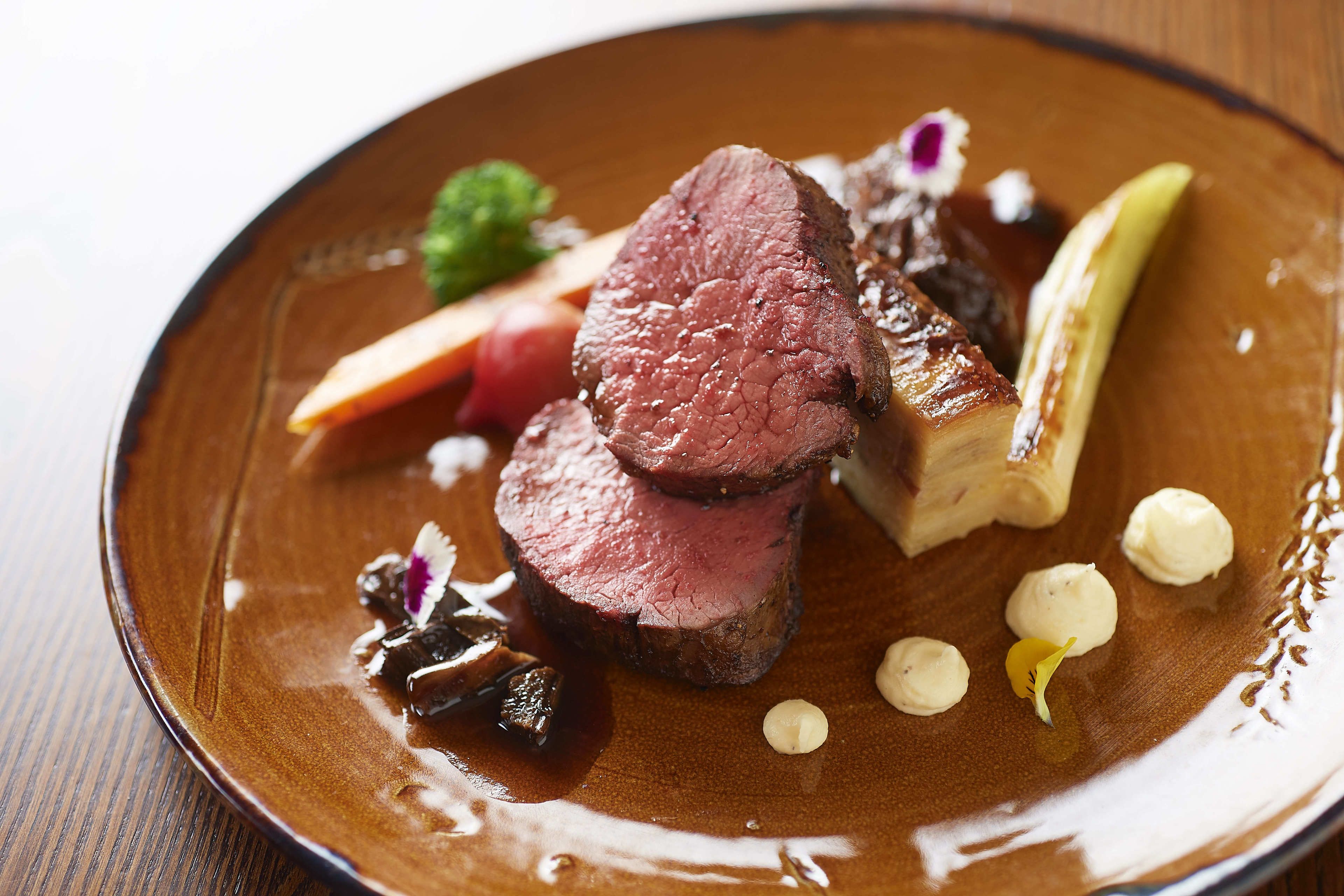 Prato de comida com fatias de carne, legumes e molhos.