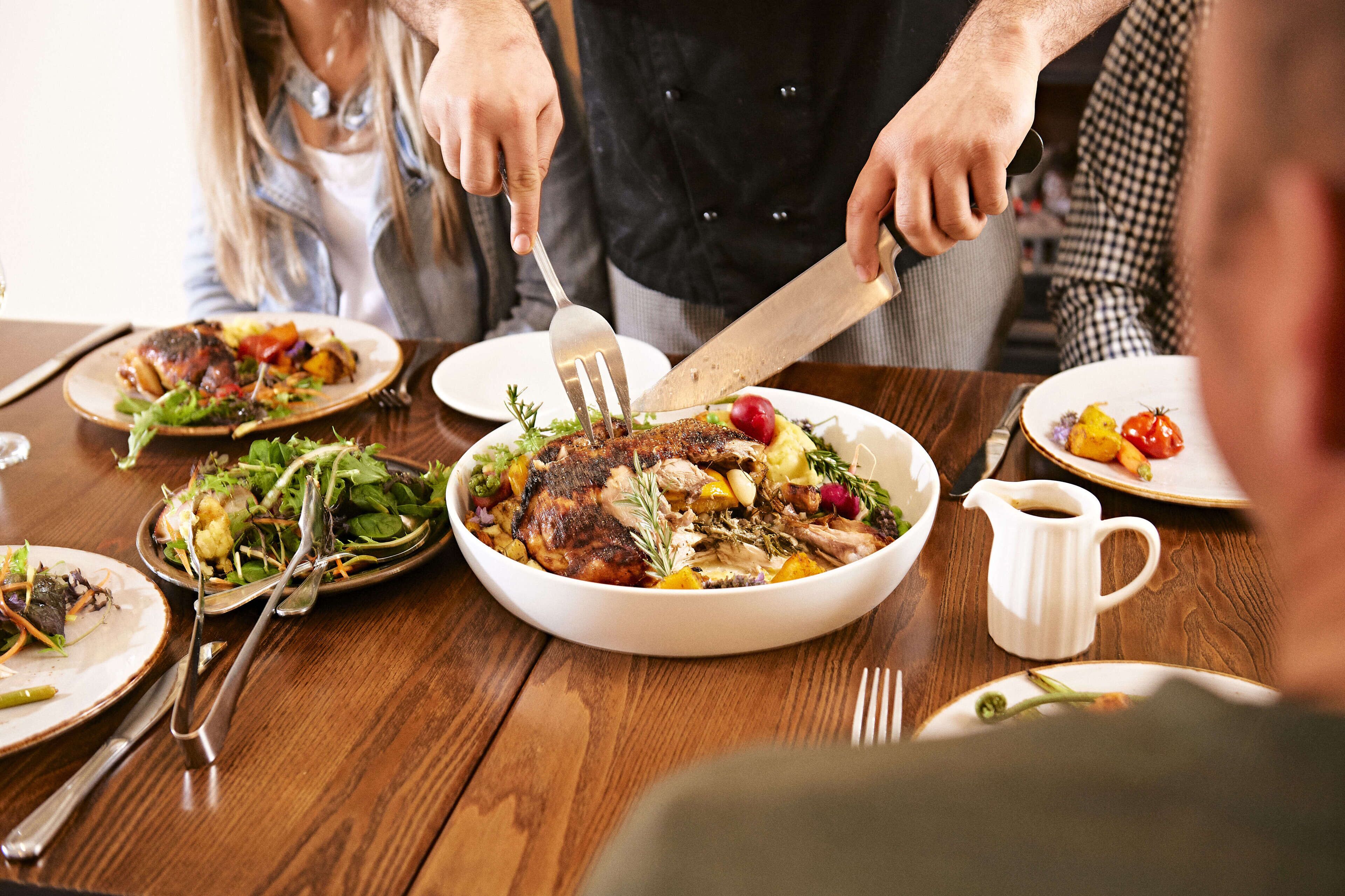 Une table à manger avec différents plats, notamment un poulet rôti, une salade et des légumes.