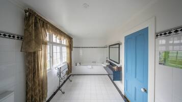 A bathroom with a bathtub, a sink, and a blue door.