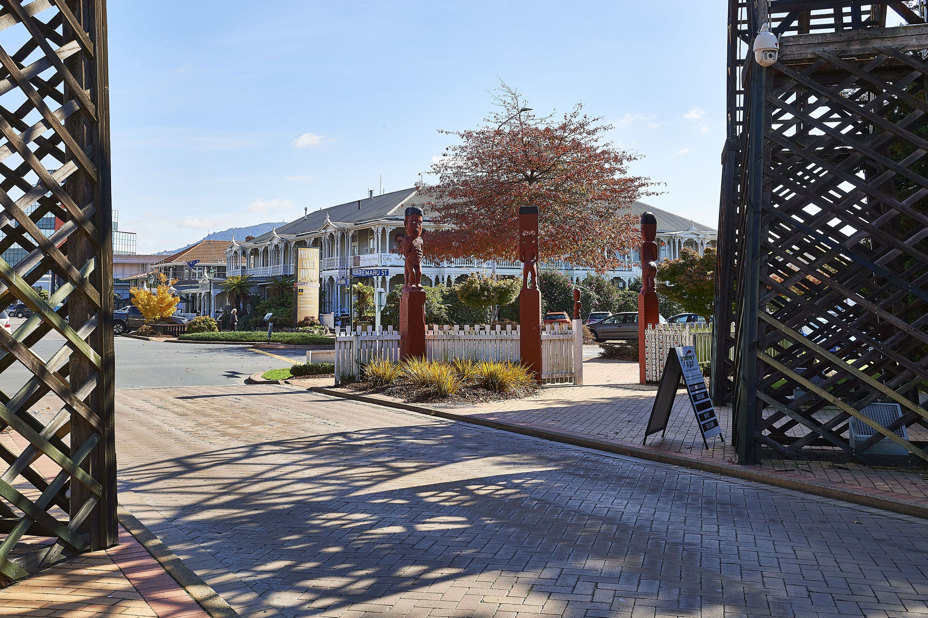 A street view with a wooden fence, a signboard, and a building with a traditional architectural style.