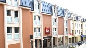 A row of hotel buildings with a consistent architectural style, featuring large windows and a prominent 'ibis' sign. - ibis Château de Fontainebleau (Fontainebleau)