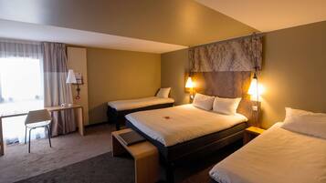 Quarto de hotel com duas camas, uma escrivaninha, uma cadeira e um pequeno banco.