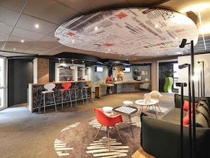 Un interior moderno con mostrador de recepción, zona de bar, asientos y un diseño de techo original.