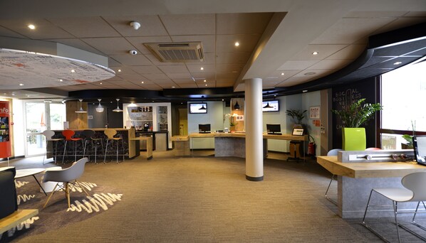 A modern office space with a reception desk, bar area, and seating.
