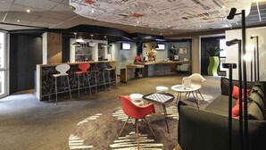 A modern interior with a bar area, seating, and a unique ceiling design. - ibis Château de Fontainebleau (Fontainebleau)
