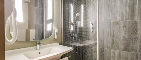 A modern bathroom with a large mirror, a sink, and a shower enclosure.